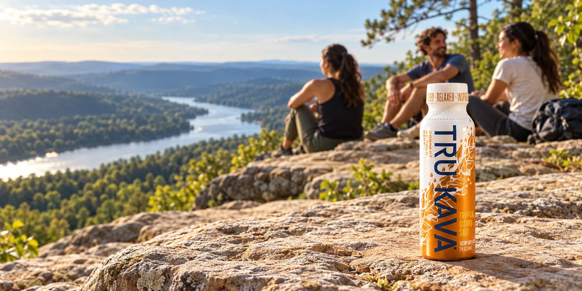 A TRU KAVA Tropical Citrus Shot on a sunlit rocky bluff above a river valley as hikers rest nearby