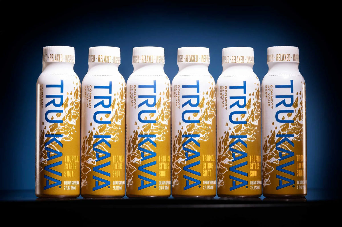 Six TRU KAVA Tropical Citrus Kava Shots in a row against a dark blue studio backdrop