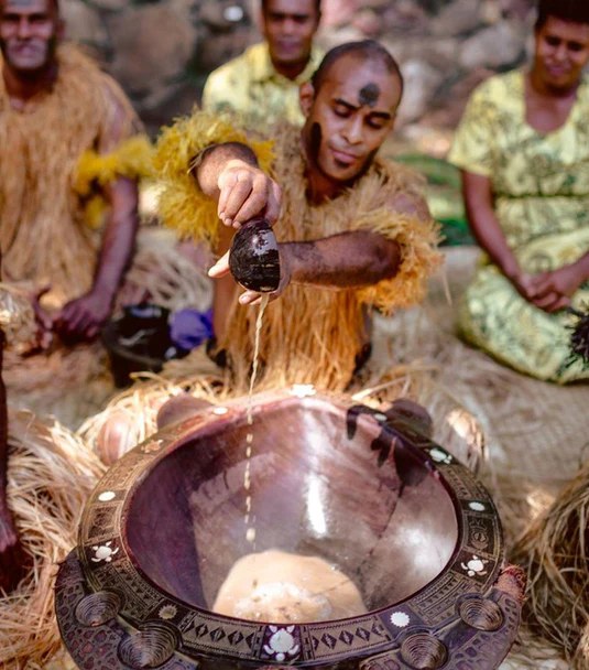 People gathered around a traditional kava bowl as kava is prepared and served