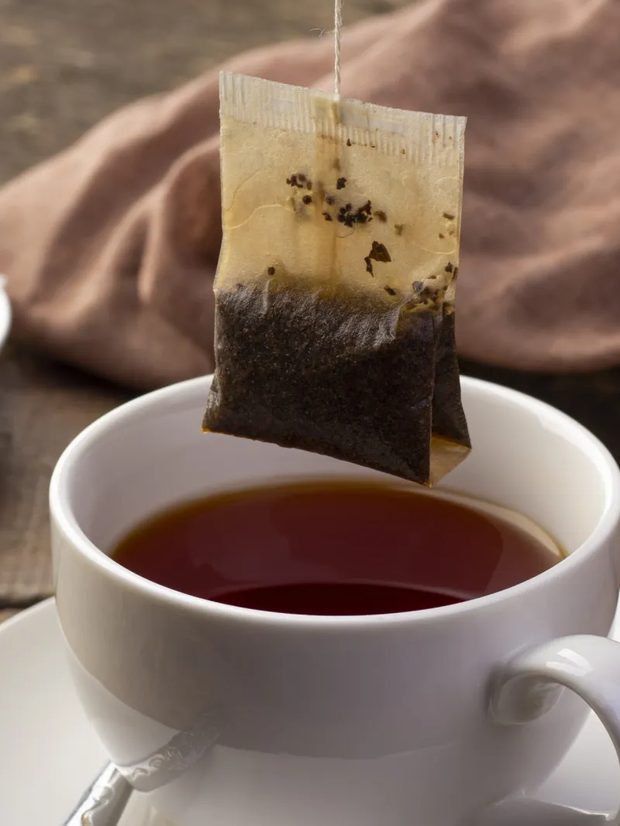 A tea bag being lifted from a cup of tea