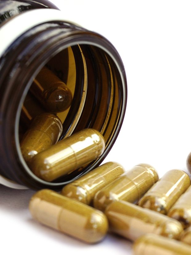 Herbal capsules spilling from an amber bottle