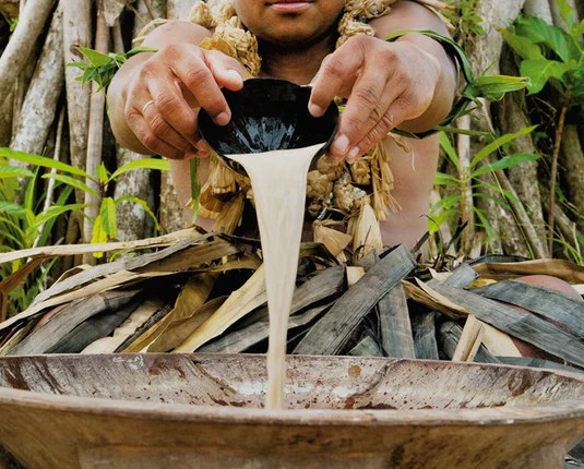Traditionally prepared kava being poured outdoors into a carved bowl