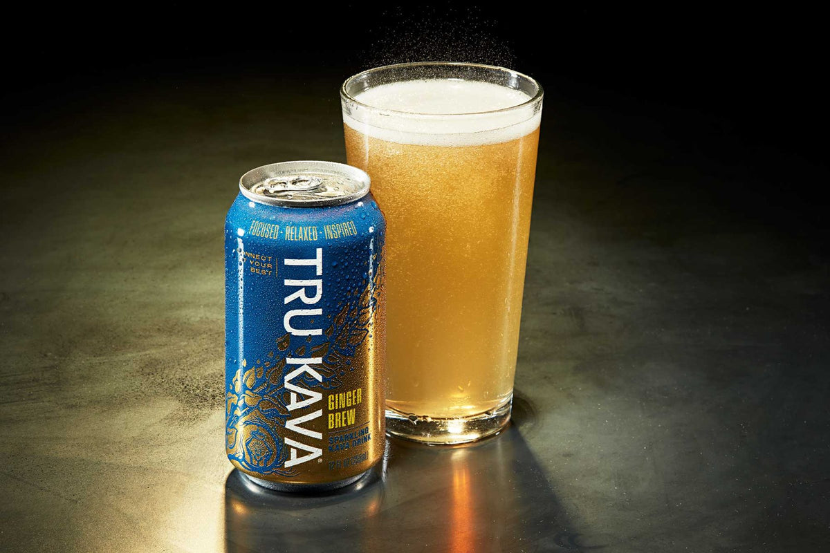An upright TRU KAVA Ginger Brew can beside a freshly poured glass